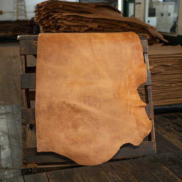 Large piece of brown leather on a wooden pallet in an indoor setting